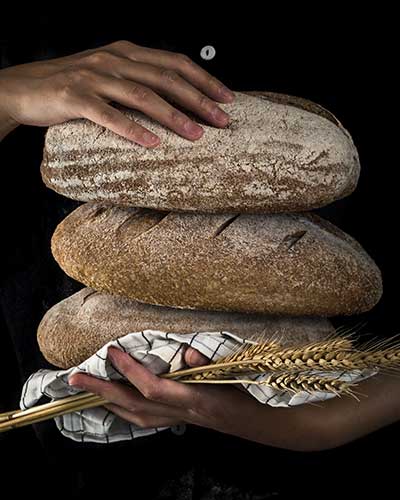 Hands holding bread and wheat